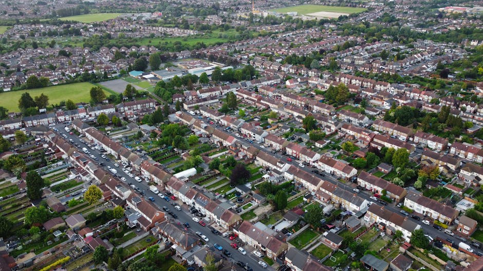 An aerial view of a residential neighbourhood in Romford, showing rows of terraced houses with pitched roofs, small front gardens, and paved walkways. The street is lined with parked cars on both side